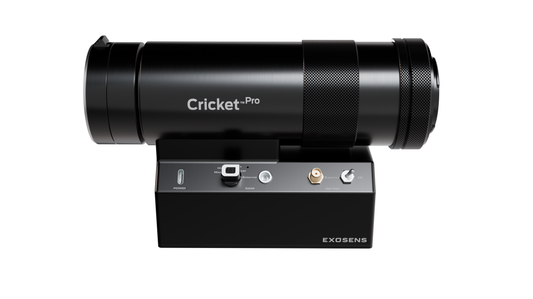 Black, cylindrical Cricket™ Pro imaging device mounted on a compact base, featuring a large front optical lens, textured grip rings, and front-panel controls and connectors; branded “Exosens” on the base, shown against a dark background.